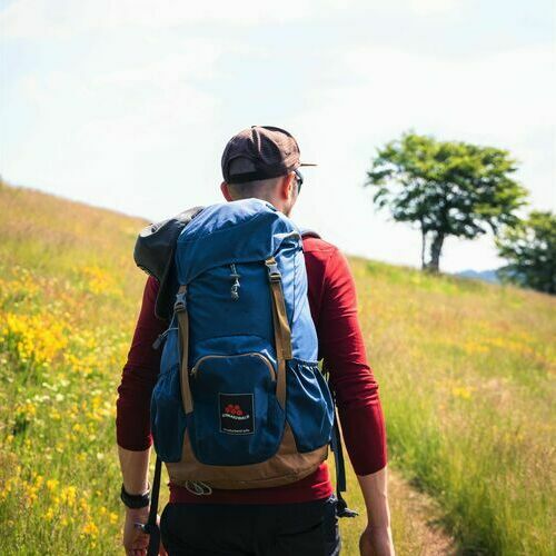Wanderer auf blühender Wiese mit Wanderrucksack