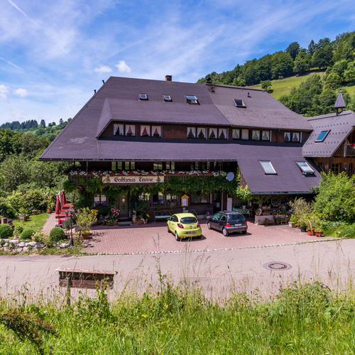 Blick auf das Gasthaus Tanne mit Parkplatz, Eingangsbereich und Terrasse - 