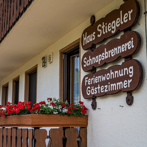 Holzschilder an der Hausfassade mit der Beschriftung Haus Stiegeler, Schnapsbrennerei und Ferienwohnung, Gästezimmer  - 