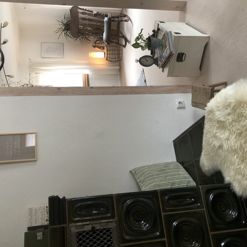 Blick vom Kachelofen auf einen Schaukelstuhl im Wohnzimmer - Blick vom Kachelofen auf einen Schaukelstuhl im Wohnzimmer -